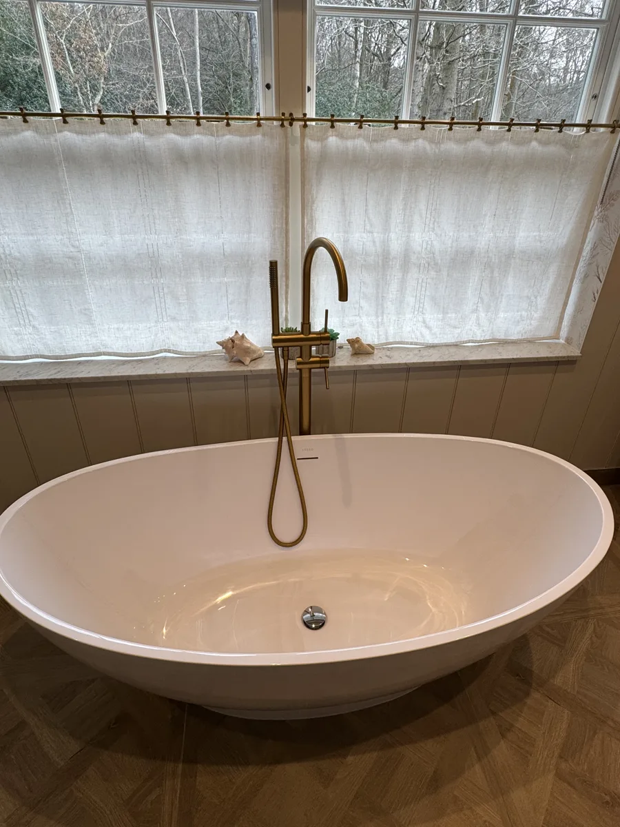 Freestanding bath with floor-standing brushed brass tap